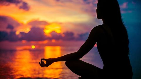 Frau meditierend am Strand - Foto: Adobe Stock/ guruXOX