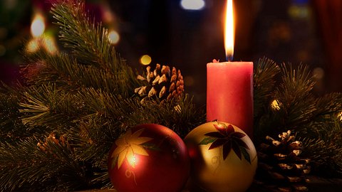 Rote Kerze umringt von Christbaumkugeln und Tannenzweigen - Foto: CreativaImages / iStock