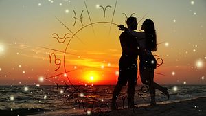 Ein verliebtes Paar steht am Strand im Sonnenuntergang. Davor ist ein Sternzeichen-Kreis zu sehen. - Foto:  New Africa / AdobeStock