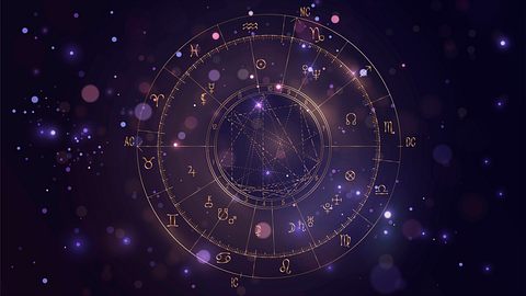 Astrologischer Sternzeichenkreis in lila vor einem dunklen Hintergrund. - Foto: Lidiia Moor / iStock