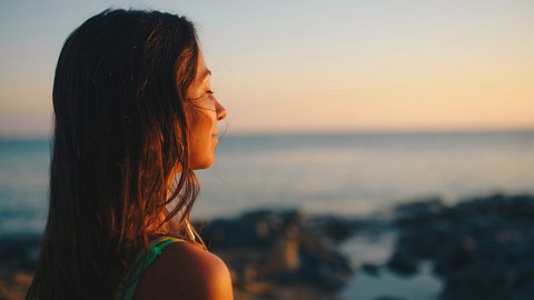 Frau steht mit geschlossenen Augen der Sonne zugewandt - Foto: iStock/Vasil Dimitrov