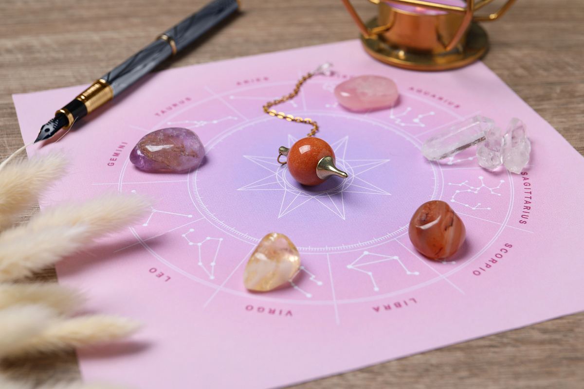 Astrologische Grafik mit Kristallen, einem Pendel und einem Stift