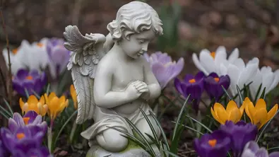 Kleine Engelstatue umgeben von Krokussen - Foto: AdobeFirefly (generiert mit KI)