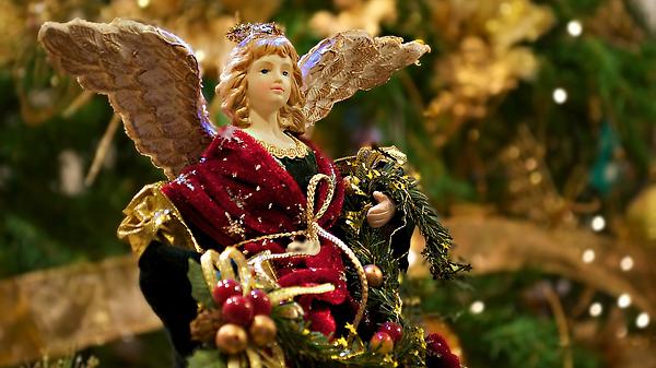 Weihnachtsengel in rotem Kleid vor einen Tannenbaum - Foto: StratosGiannikos / iStock