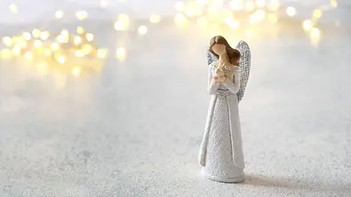 Kleine Engelstatue umgeben von Lichtern - Foto: Ju_see / AdobeStock