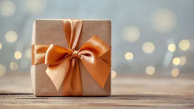Geburtstagsgeschenk mit Orangener Schleife und braunem Geschenkpapier - Foto: Volha Zaitsava / AdobeStock Geburtstagsgeschenk mit Orangener Schleife und braunem Geschenkpapier - Foto: Volha Zaitsava / AdobeStock