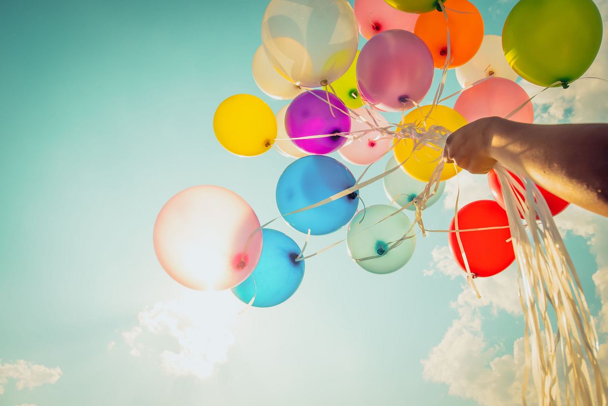 Bunte Luftballons werden in den Himmel gehalten