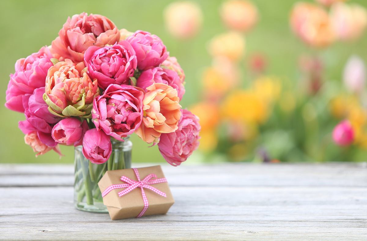 Ein Blumenstrauß und ein Geschenk auf einem Untergrund aus Holz