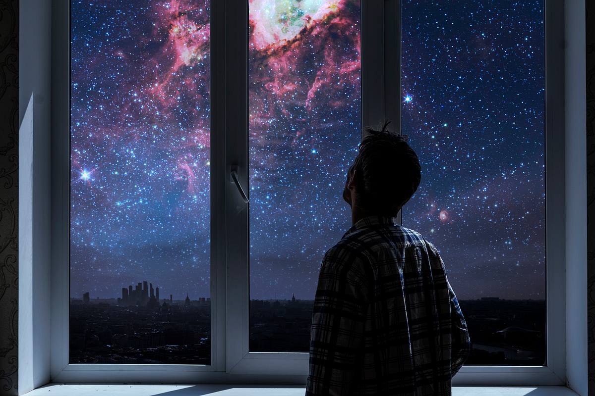 Mann beobachtet durch sein Fenster die Galaxie