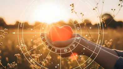 Sternzeichenkreis umringt eine Hand, die ein rotes Herz vor einem Feld im Sommer hält - Foto: Collage mit AdobeStock (Artfinity / Назарій) und Astrowoche.de