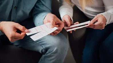 Ein Mann und eine Frau alten Lotto-Scheine in der Hand - Foto: LIGHTFIELD STUDIOS / Adobe Stock