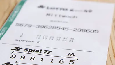 Lotto-Schein auf einem Holztisch - Foto: PhotographyByMK / AdobeStock