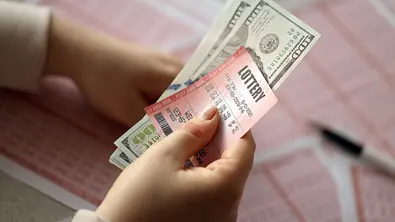 Frau hält Lotto-Scheine und Geldscheine in der Hand - Foto: mehaniq41 / AdobeStock