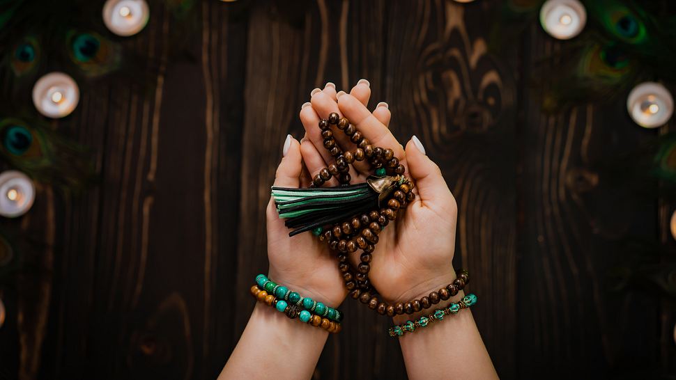 Frau hält buddhistisches Mala in der Hand - Foto: Kristina Kokhanova / iStock