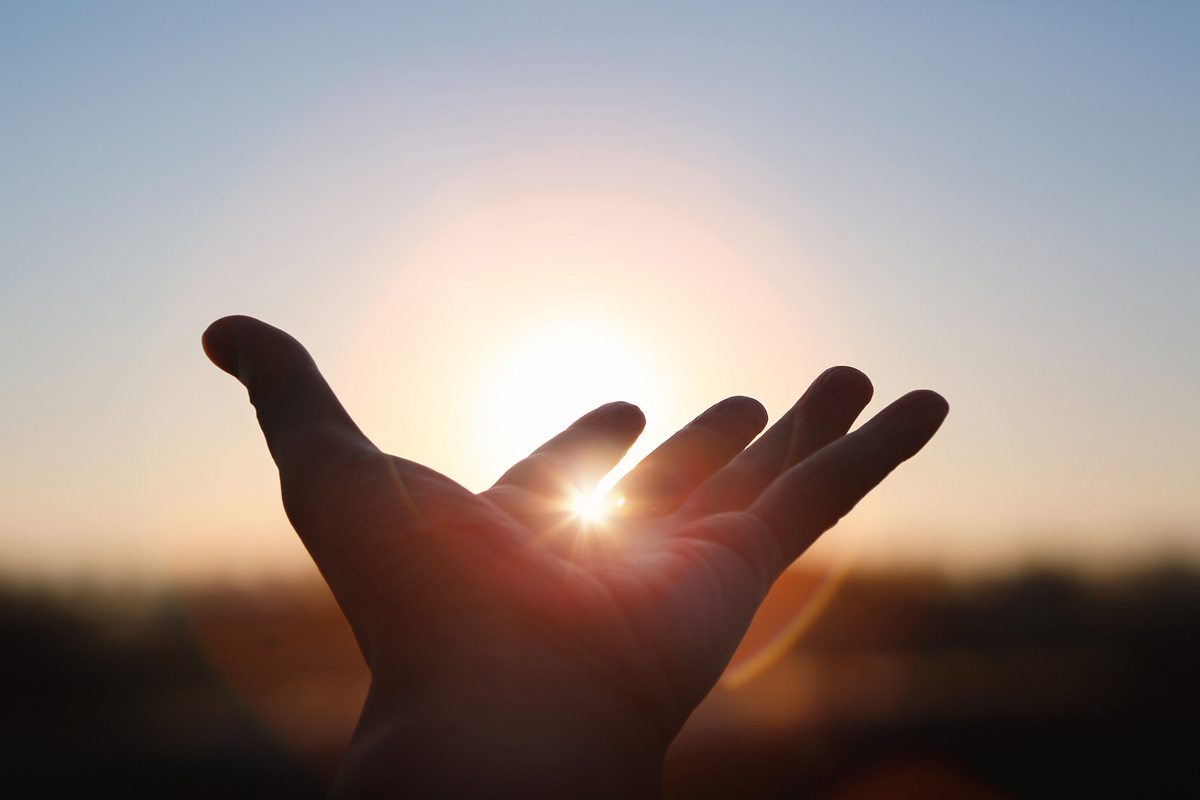 Hand wird in das Sonnenlicht gehalten