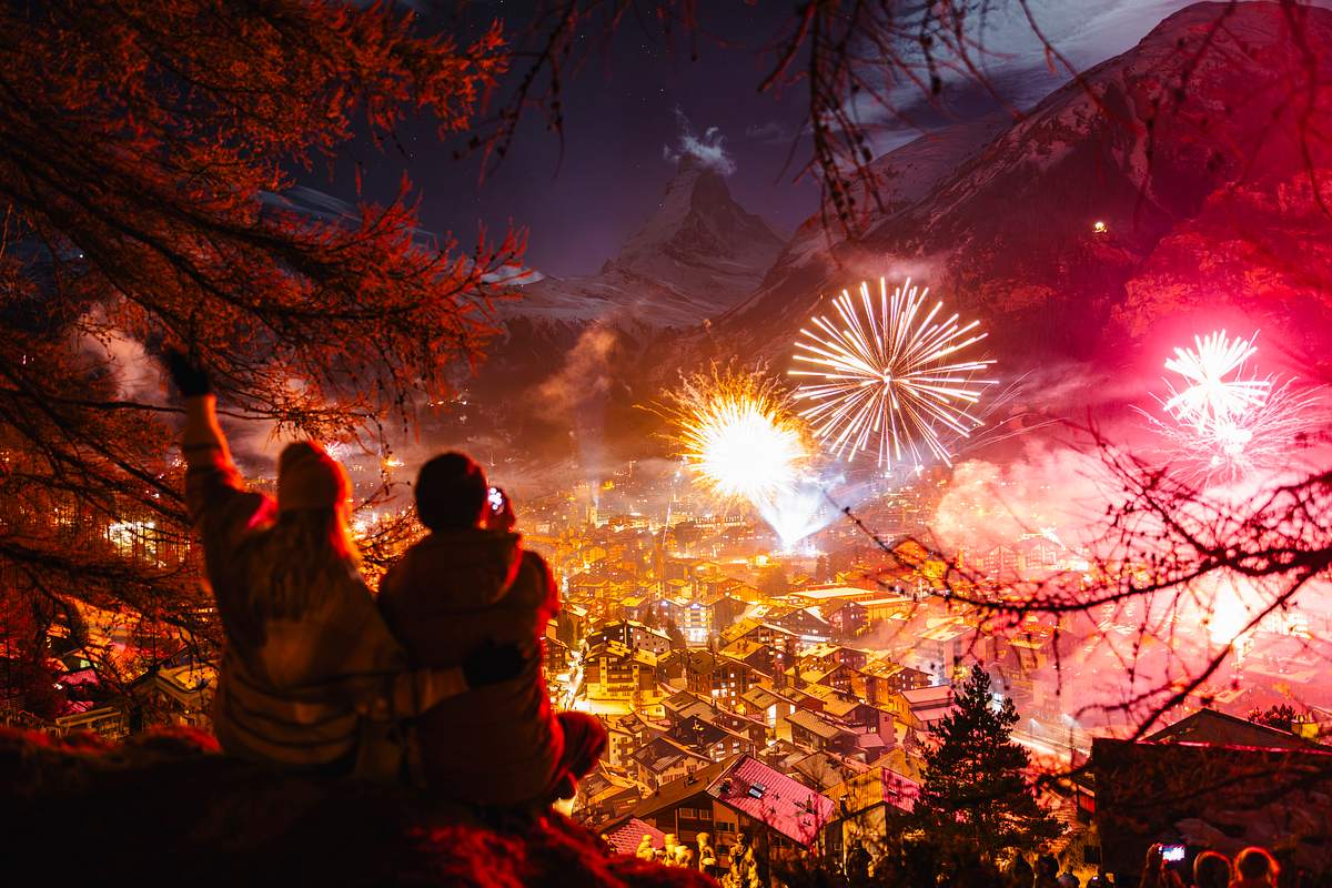 Ein Paar guckt sich von einem Hügel Feuerwerk in der Stadt an