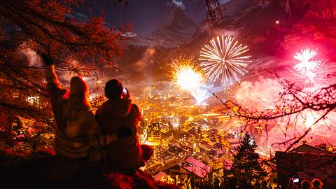 Ein Paar guckt sich von einem Hügel Feuerwerk in der Stadt an - Foto: SimonSkafar / iStock