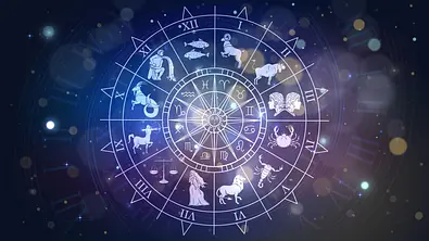 Das Bild zeigt eine Grafik des astrologischen Tierkreises vor einem dunklen Hintergrund, der mit bunten Lichpartikeln erleuchtet wird.  - Foto: Lidiia Moor/iStock