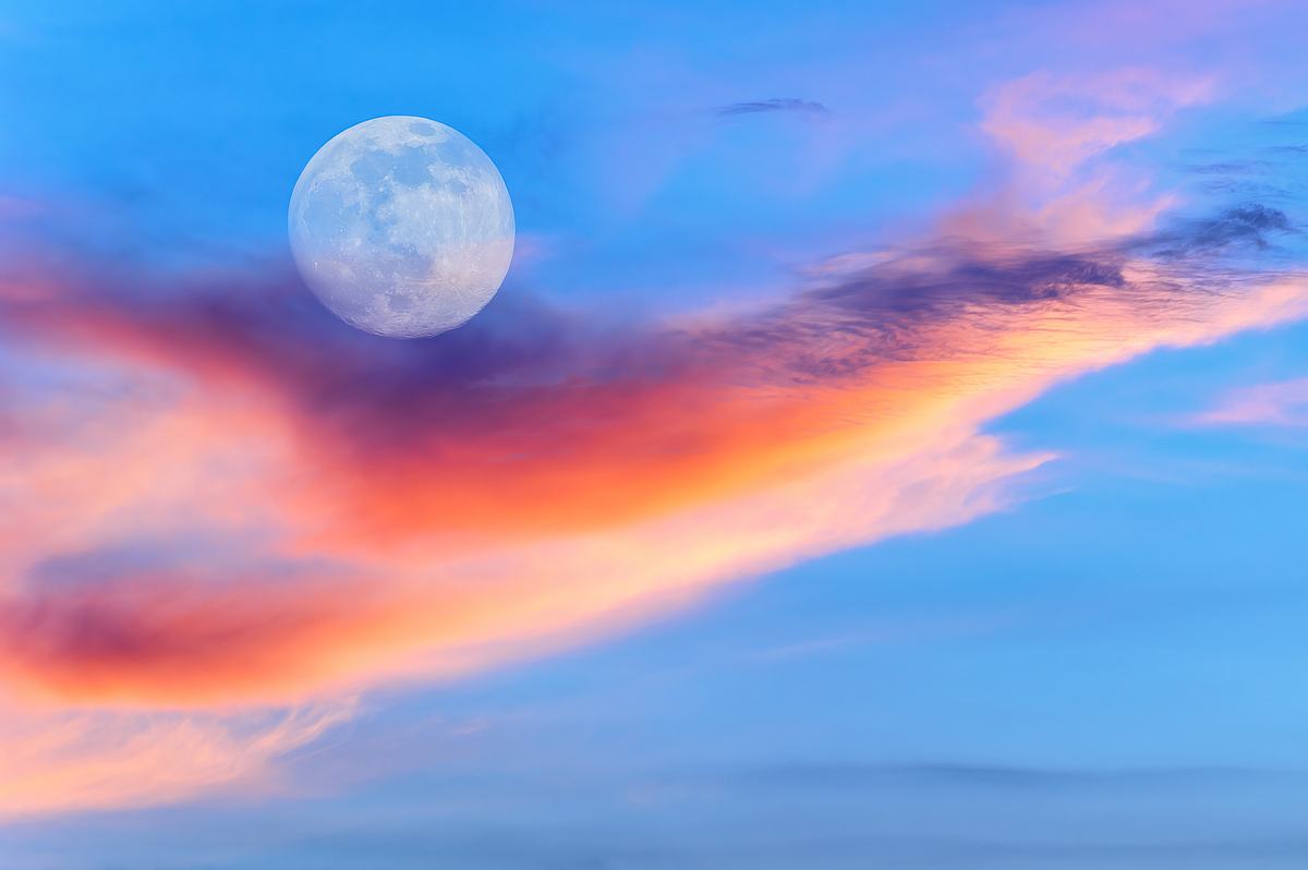 Ein leuchtender Vollmond steht am Himmel bei Sonnenuntergang