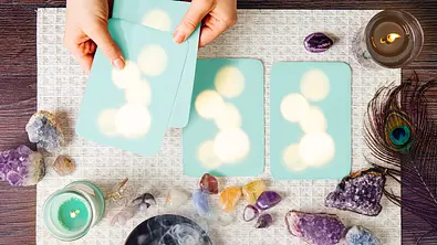 Hände legen hellblaue Tarotkarten auf eine weiße Unterlage - Foto: iStock/Helin Loik-Tomson