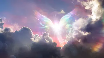 Lichtgestalt mit Flügeln zwischen Wolken als Symbol für das Engeltarot - Foto: iStock/RomoloTavani