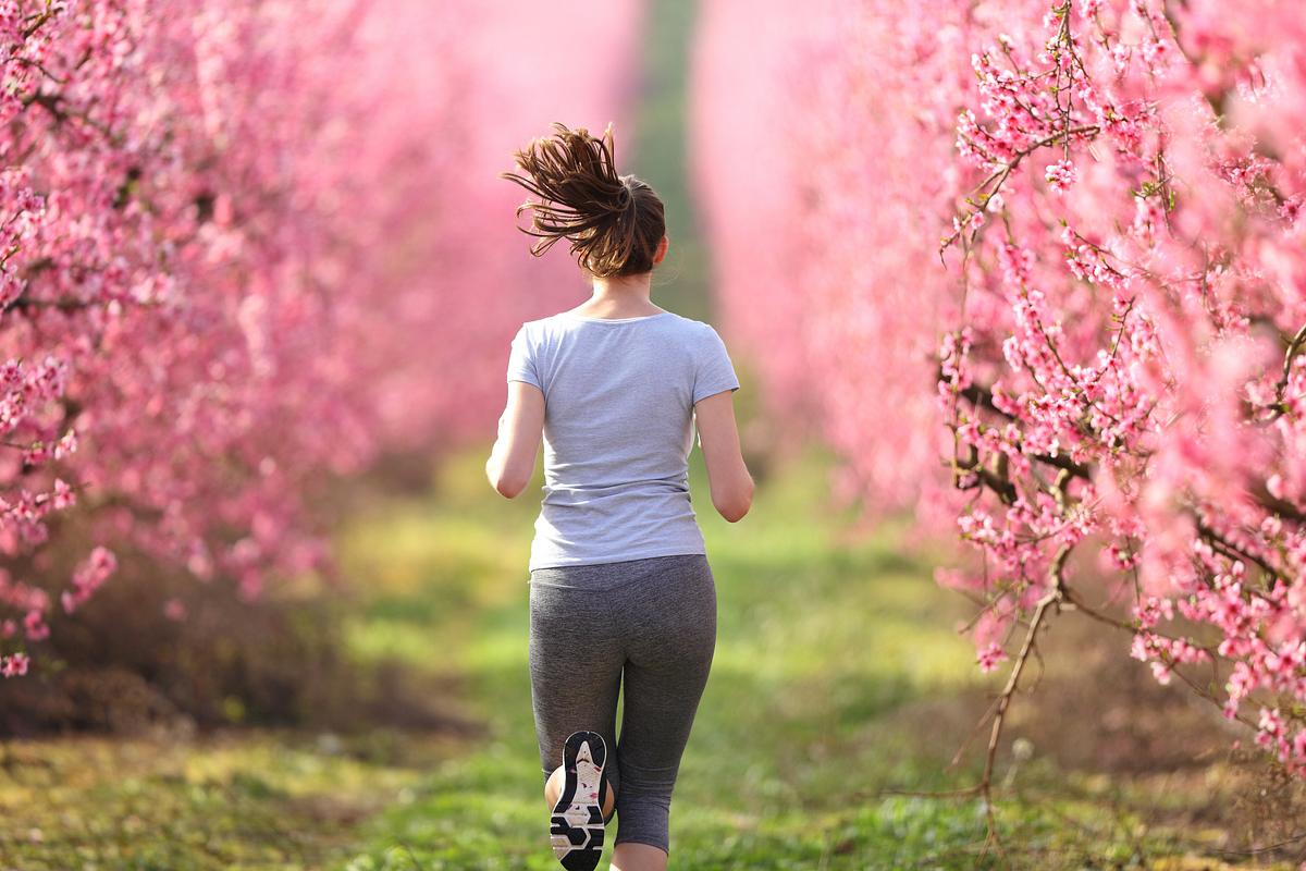 Eine Frau joggt über ein Feld umgeben von Blüten