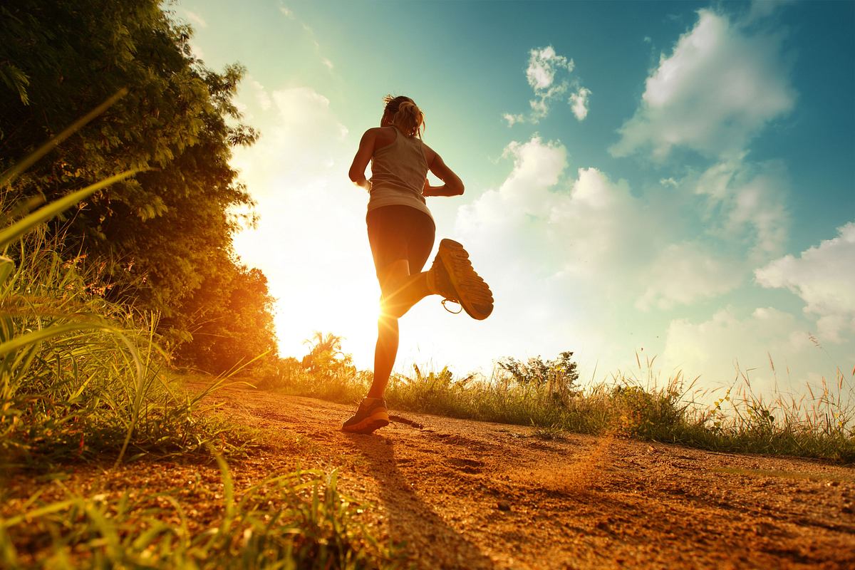 Frau joggt im Sonnenschein am Waldrand