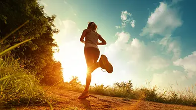 Frau joggt im Sonnenschein am Waldrand - Foto: Dudarev Mikhail / AdobeStock