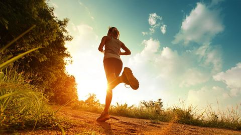 Frau joggt im Sonnenschein am Waldrand - Foto: Dudarev Mikhail / AdobeStock