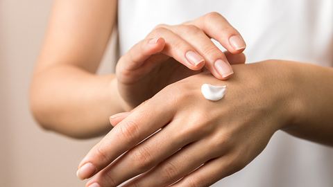 Frau cremt sich ihre Hände mit Handcreme ein. - Foto: AndreiDavid/ iStock