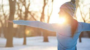 Frau streckt sich im Winter draußen  - Foto: julief514/ iStock