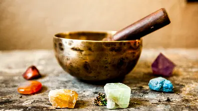 Klangschale in einem Halbkreis aus Edelsteinen - Foto: iStock/Renphoto