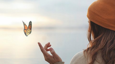 Frau hält ihren Finger in Richtung eines Schmetterlings - Foto: fcscafeine/iStock