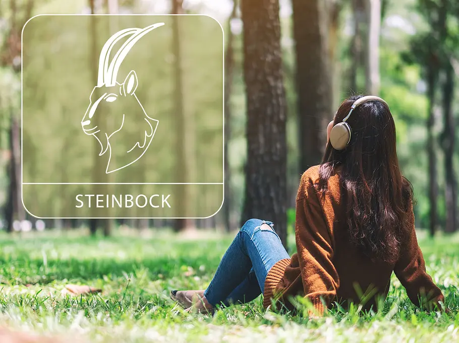 Frau mit Kopfhörern in einem sonnigen Wand neben dem Sternzeichen Steinbock