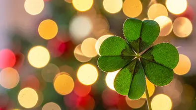 Glücksklee vor einem weihnachtlichen Hintergrund - Foto: AdobeFirefly (generiert mit KI)