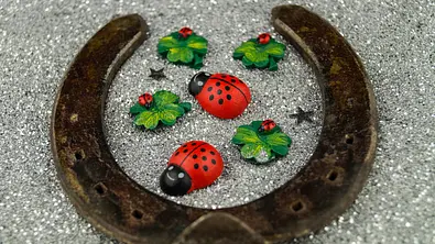 Ein Hufeisen kreist Marienkäfer und Glücksklee ein - Foto: Andreas Steidlinger / iStock