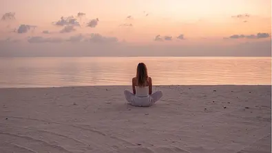 Frau sitzt am Meer - Foto: iStock/Mystockimages