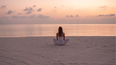 Frau sitzt am Meer - Foto: iStock/Mystockimages