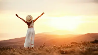 Frau steht dem Sonnenuntergang zugewandt - Foto: iStock/evgenyatamanenko
