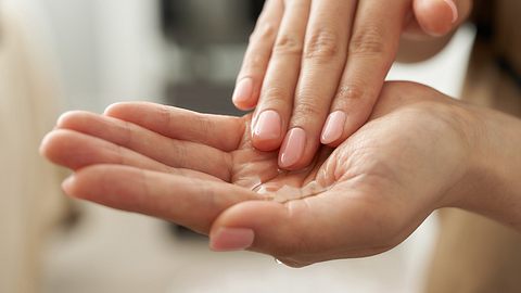 Frau verreibt Öl in ihren Händen - Foto: mapo / iStock