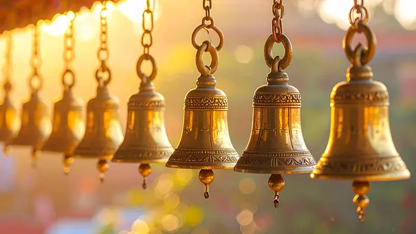 Goldene Glocken hängen von goldenen Ketten im Sonnenlicht - Foto: P / AdobeStock Goldene Glocken hängen von goldenen Ketten im Sonnenlicht - Foto: P / AdobeStock
