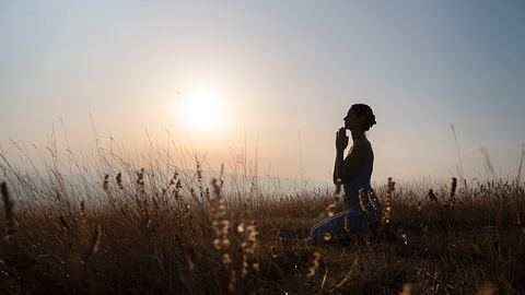 Frau die zum Sonnenaufgang betet - Foto: iStock/ nemke  