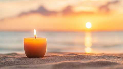 Kerze steht am Strand bei Sonnenuntergang - Foto: Anna / AdobeStock
