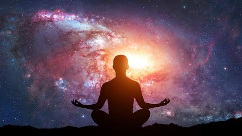 Mann meditiert vor galaktischem Hintergrund - Foto: dima_zel / iStock
