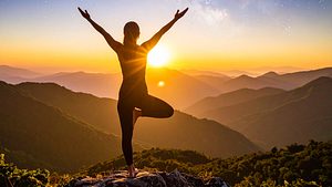 Frau macht Yoga auf einem Berg im Sonnenuntergang und streckt ihre Hände den Sternen entgegen - Foto: AdobeFirefly (generiert mit KI)
