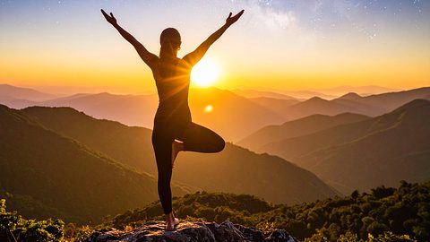Frau macht Yoga auf einem Berg im Sonnenuntergang und streckt ihre Hände den Sternen entgegen - Foto: AdobeFirefly (generiert mit KI)