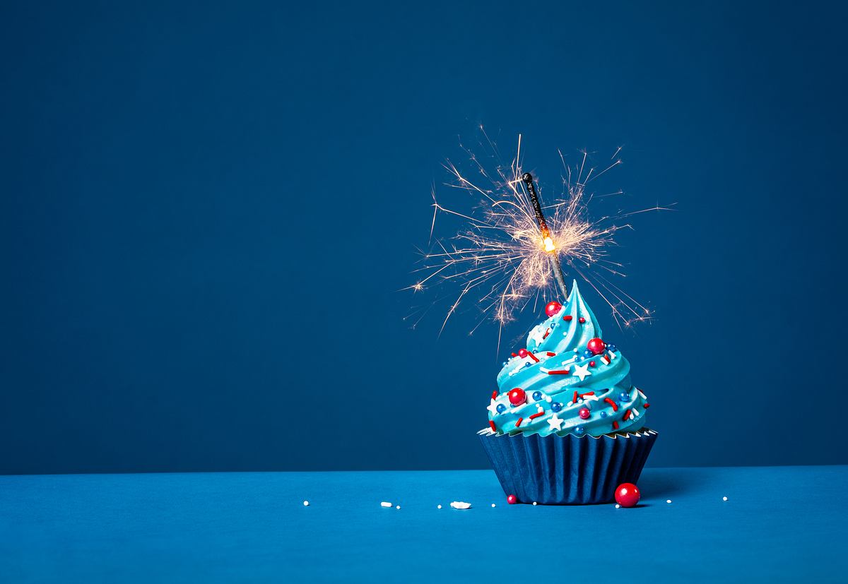 Ein blauer Cupcake mit Wunderkerzen vor einem dunkelblauen Hintergrund