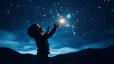 Ein Kind greift nach den Sternen am Nachthimmel - Foto: mertingen / AdobeStock