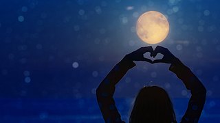 Frau formt Herz mit den Händen vor dem Nachthimmel - Foto: m-gucci/iStock