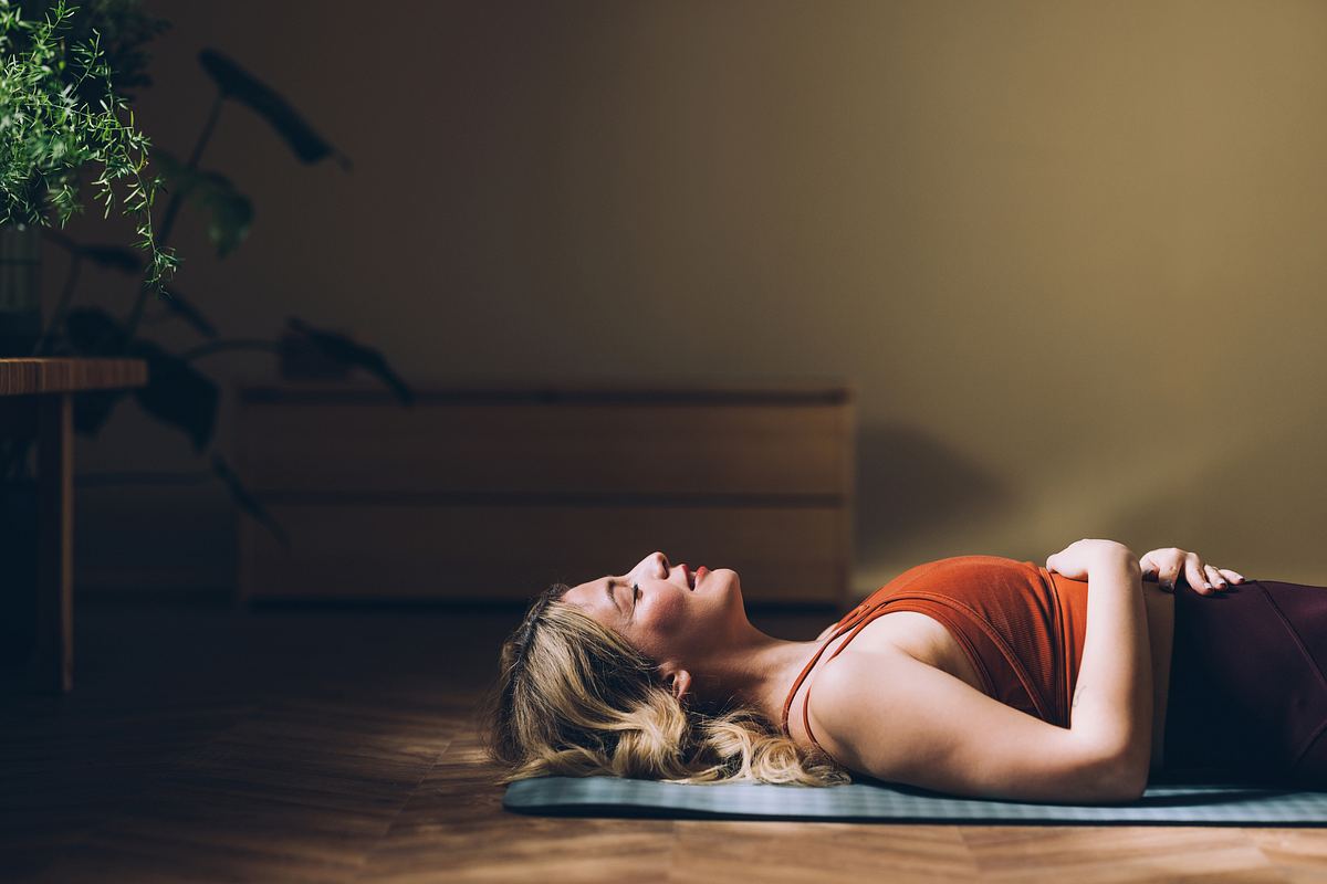 Frau liegt meditierend auf einer Yoga-Matte